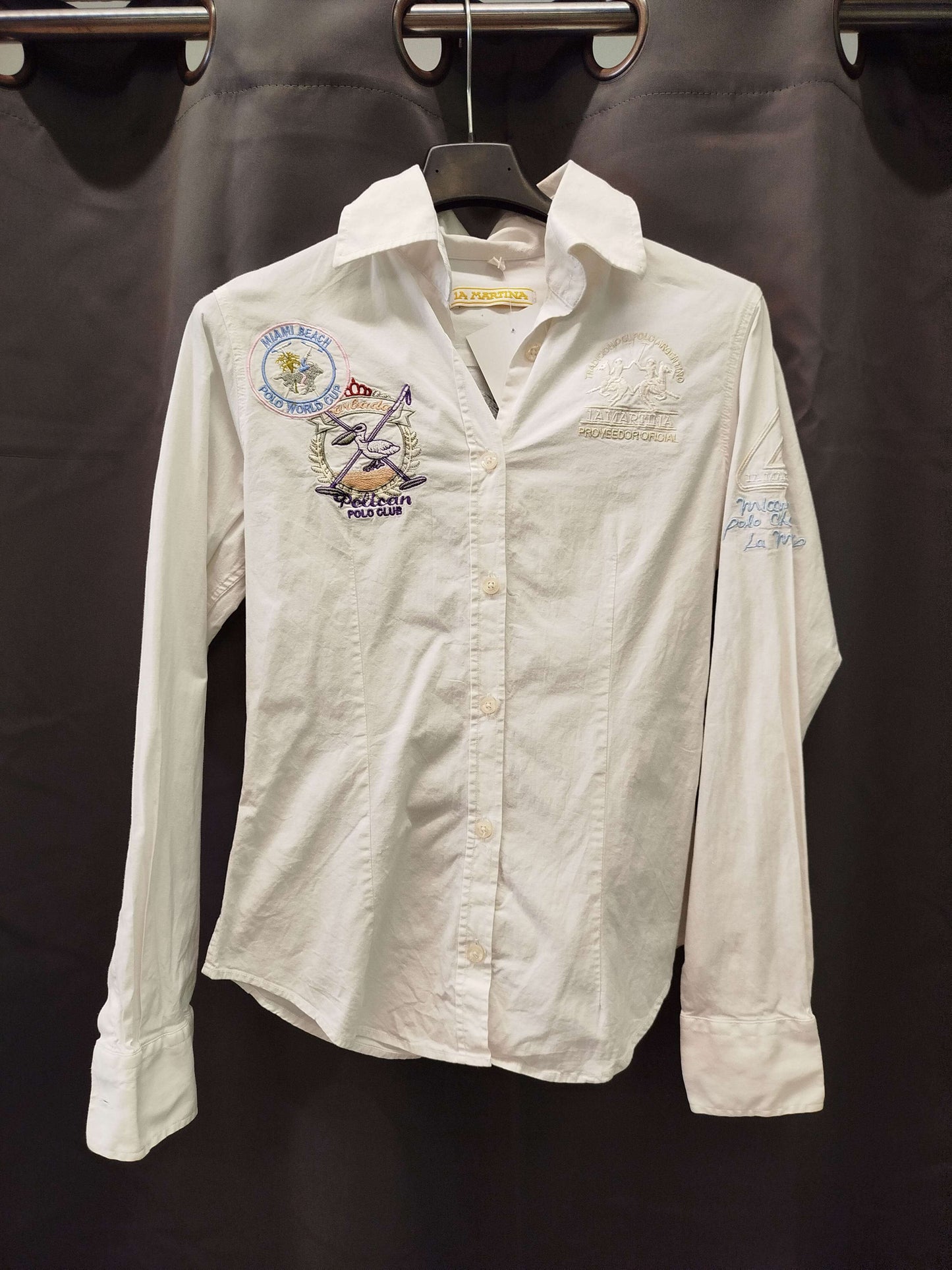 Camicia La Martina size S, white shirt with embroidery, in excellent condition, hanging on a display.